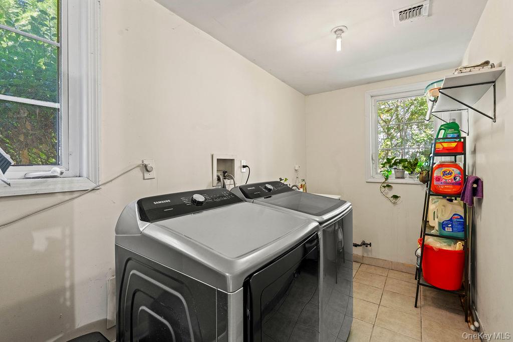 60 Plymouth Road Great Neck, NY 11023 - Photo 31 of 36 Laundry area with light tile patterned floors and washer and dryer