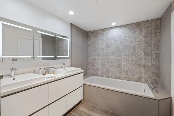 a bathroom with a tub a sink and mirror