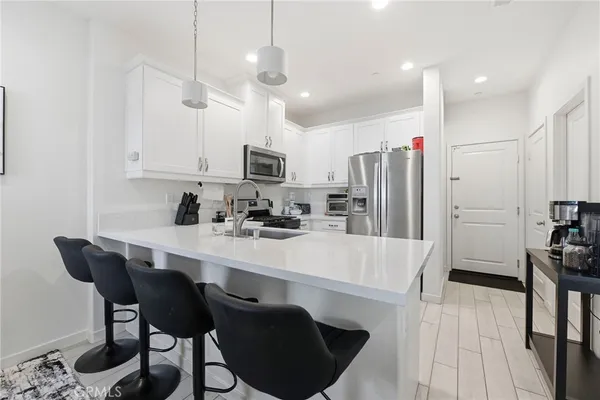 a kitchen with granite countertop a sink a white cabinets and chairs