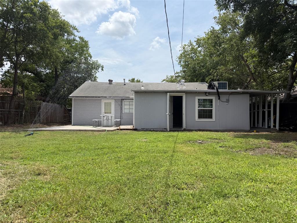 714 Southwest Dallas Street Grand Prairie, TX 75051 - Photo 27 of 27 Expansive backyard featuring a concrete patio, mature trees, and a covered side area