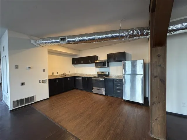 a view of kitchen with granite countertop stainless steel appliances counter space and wooden floor