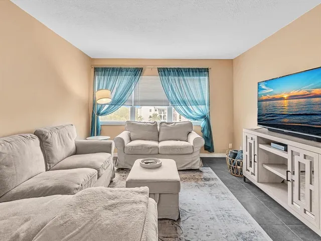 a living room with furniture flat screen tv and a large window
