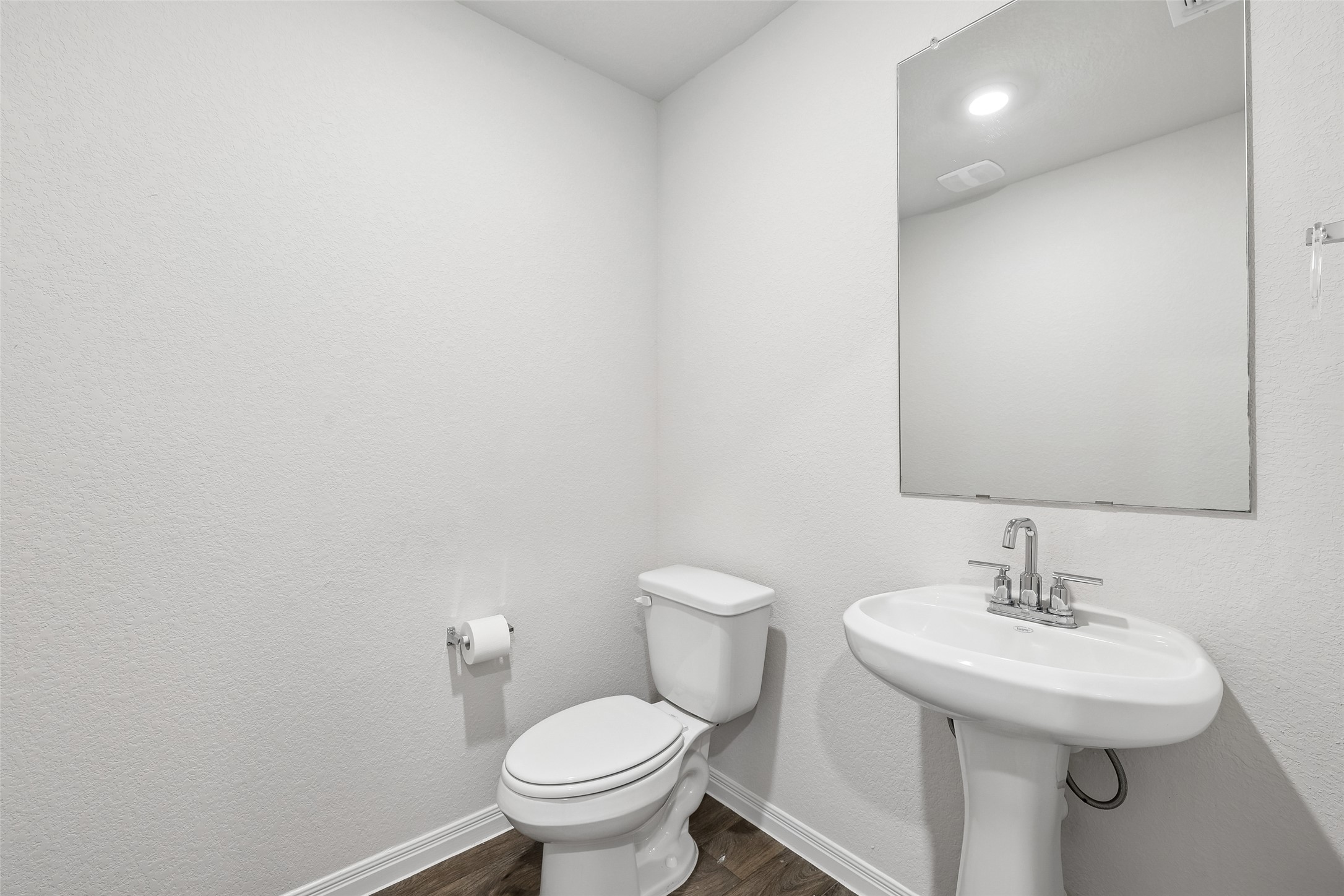 19805 Abigail Fillmore Road Manor, TX 78653 - Photo 26 of 40 A compact and functional powder room with a sleek pedestal sink and wood-look flooring.