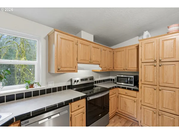 a kitchen with stainless steel appliances granite countertop a stove a sink and white cabinets
