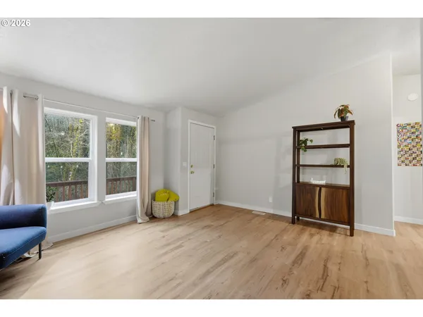 a view of an empty room with wooden floor and windows