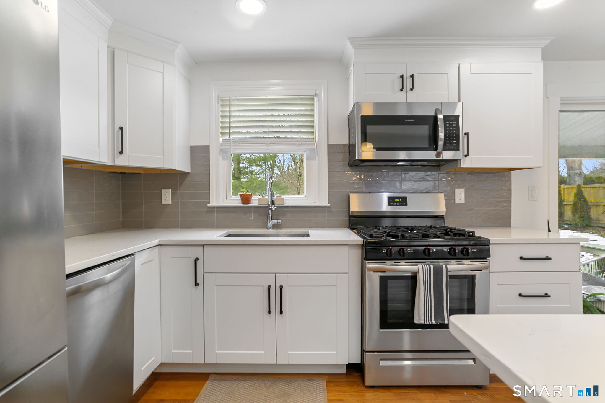 1353 Mill Plain Road Fairfield, CT 06824 - Photo 10 of 37 a kitchen with white cabinets stainless steel appliances and sink