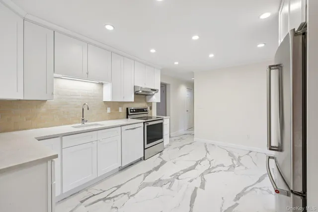 a kitchen with white cabinets and stainless steel appliances