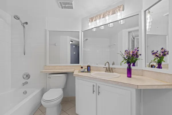 a bathroom with a sink a toilet a mirror a vanity a bathtub and shower