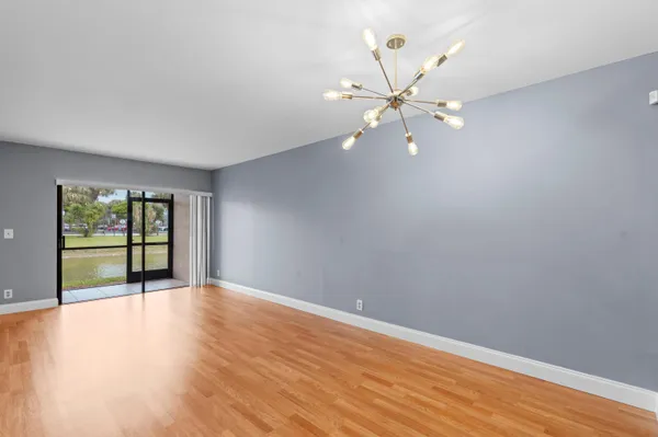 a view of an empty room with window and wooden floor