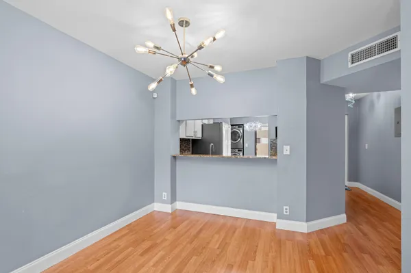 a view of an empty room with wooden floor and a ceiling fan