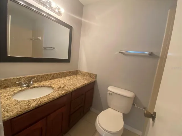 a bathroom with a granite countertop toilet sink and mirror