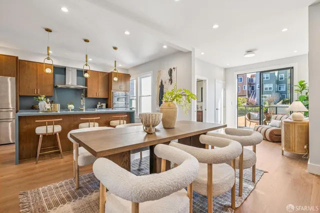 a kitchen with stainless steel appliances granite countertop a stove a sink a refrigerator a dining table and chairs