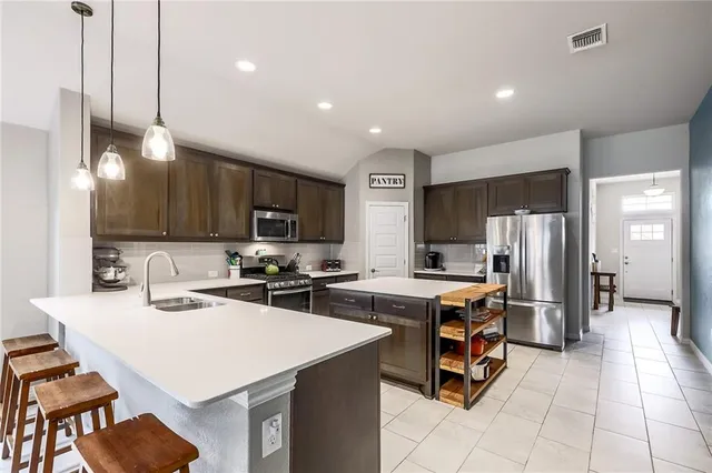 a kitchen with a sink a stove a refrigerator and chairs