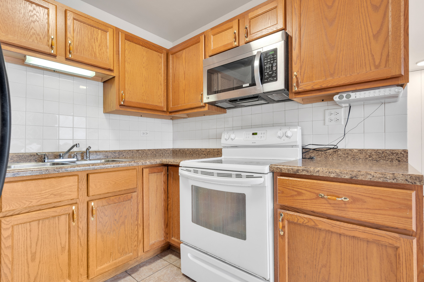 4343 North Clarendon Avenue, Unit 707 Chicago, IL 60613 - Photo 5 of 24 a kitchen with granite countertop white cabinets stainless steel appliances and a sink