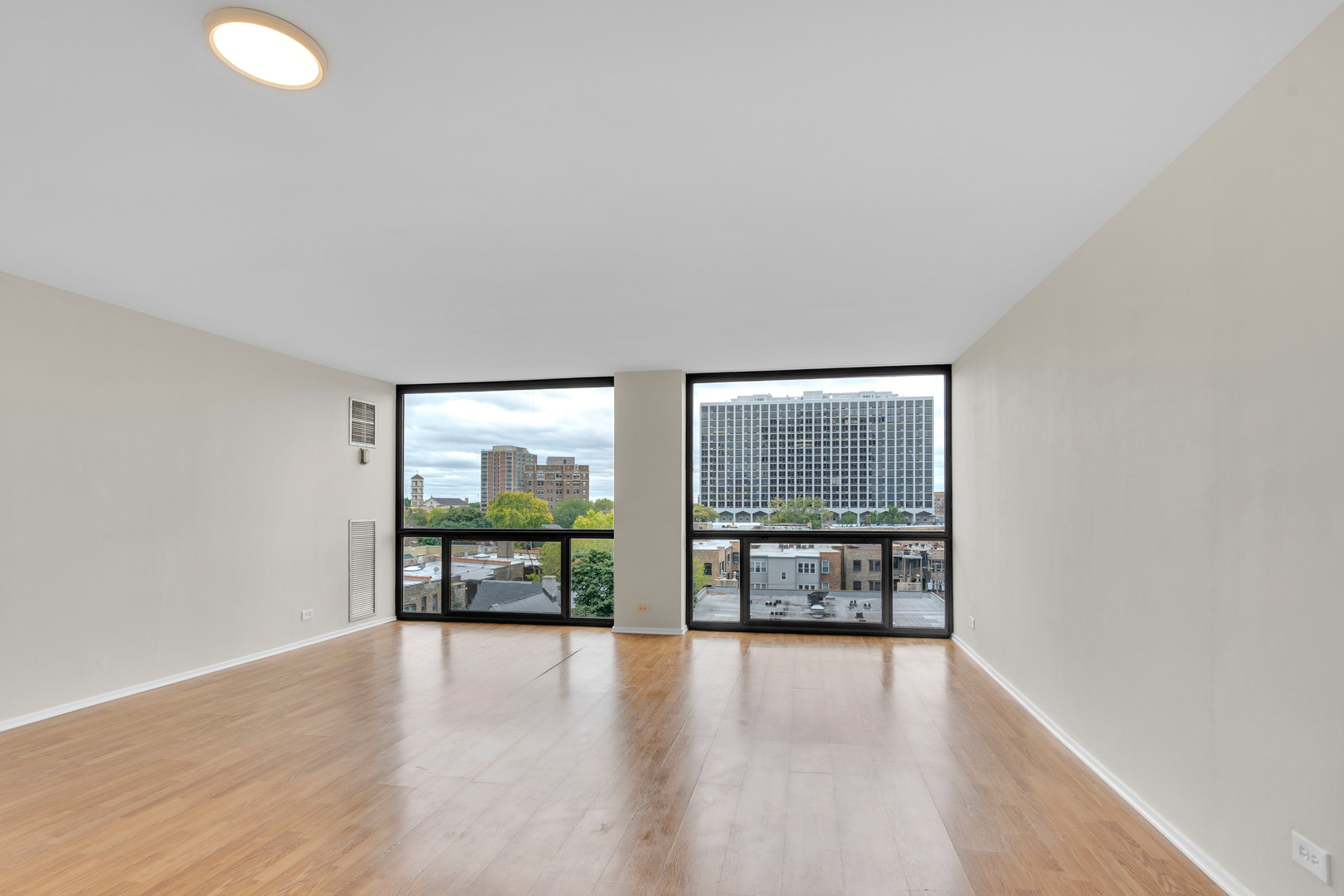 4343 North Clarendon Avenue, Unit 707 Chicago, IL 60613 - Photo 9 of 24 a view of an empty room with wooden floor and a window