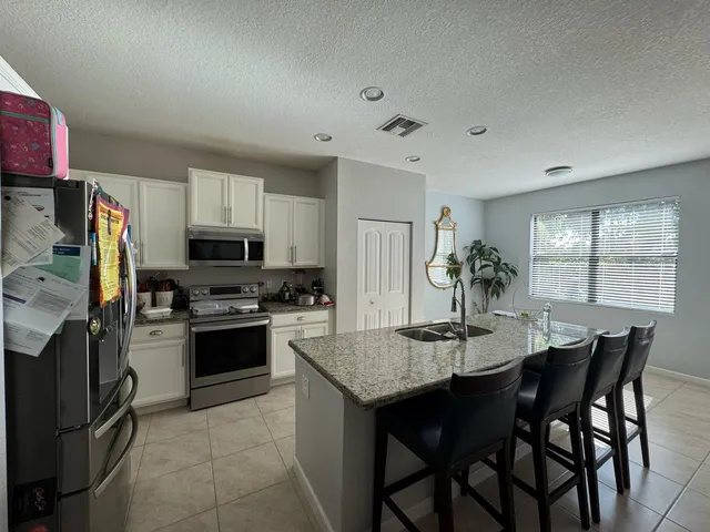 a kitchen with stainless steel appliances granite countertop a dining table and chairs in it