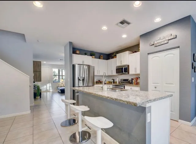 a large kitchen with a counter space a sink and chairs