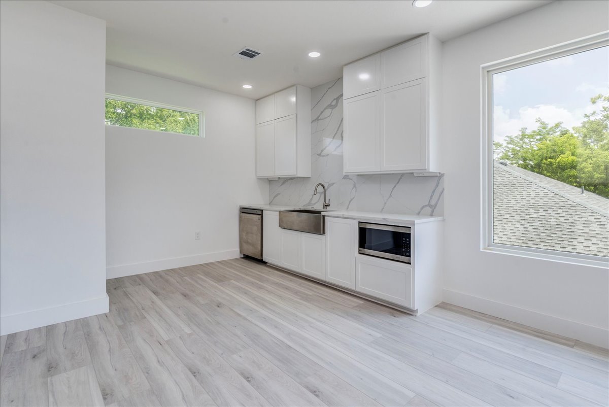 1215 Howard Street Taylor, TX 76574 - Photo 26 of 37 Kitchen with appliances with stainless steel finishes, light countertops, recessed lighting, white cabinetry, and light wood-style floors