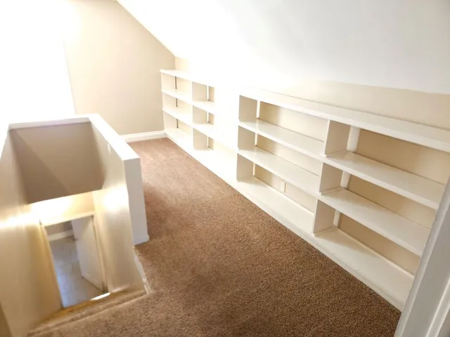 a view of an empty room with wooden floor and windows