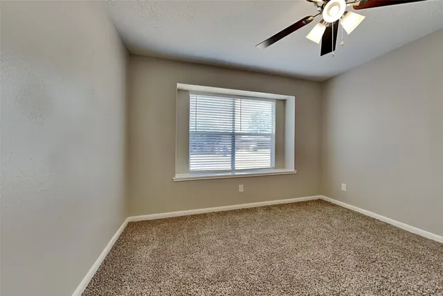 an empty room with windows and chandelier fan