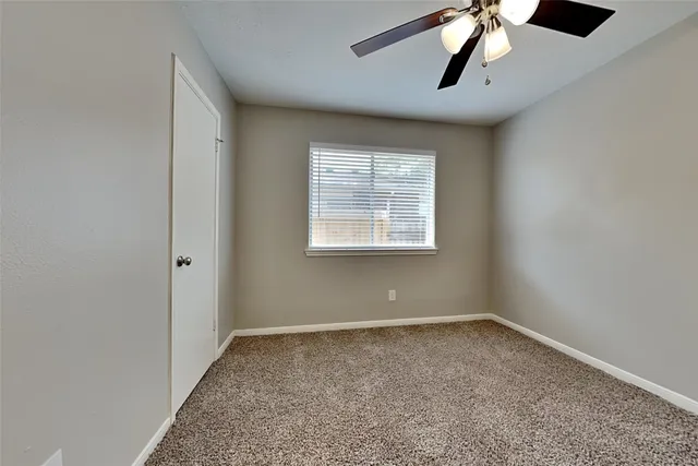 an empty room with a window and a ceiling fan