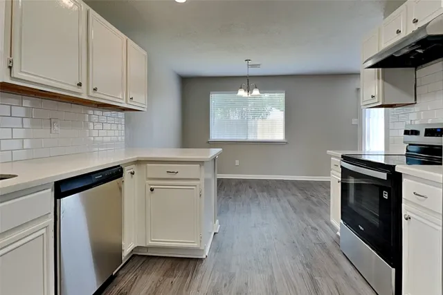 a kitchen with stainless steel appliances a white stove top oven cabinets and a wooden floor