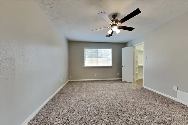 an empty room with windows and ceiling fan