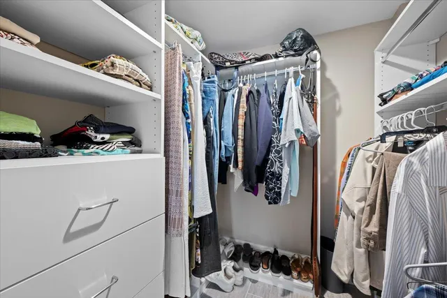 a view of walk in closet with clothes and shoes