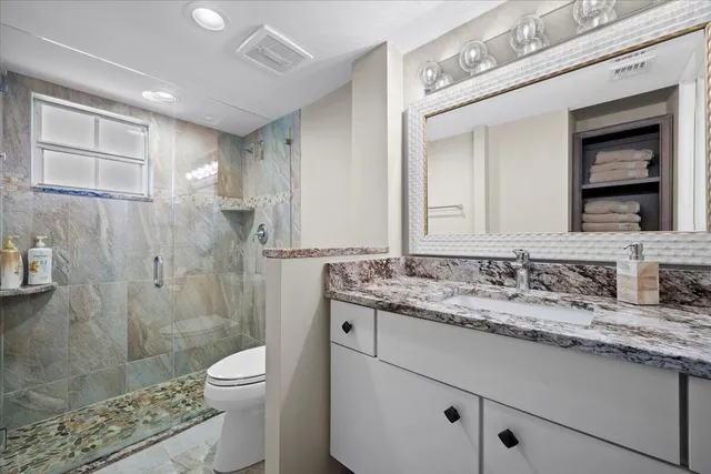 a bathroom with a granite countertop sink a toilet and shower
