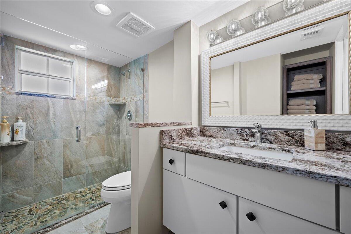 1252 Sugar Sands Boulevard, Unit 132 Riviera Beach, FL 33404 - Photo 20 of 40 a bathroom with a granite countertop sink a toilet and shower