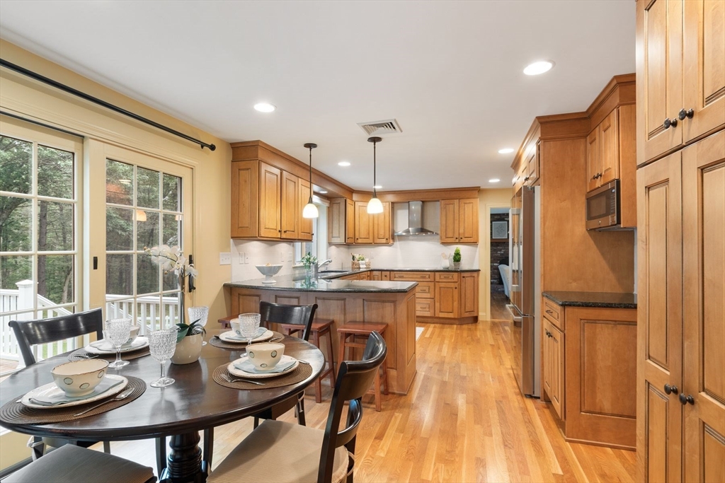 244 Hunters Ridge Road Concord, MA 01742 - Photo 14 of 41 a dining room with stainless steel appliances kitchen island granite countertop furniture and wooden floor