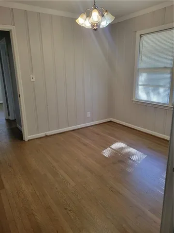 an empty room with wooden floor cabinet and windows