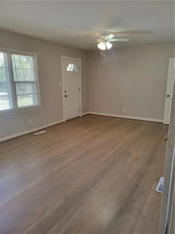 an empty room with wooden floor and windows