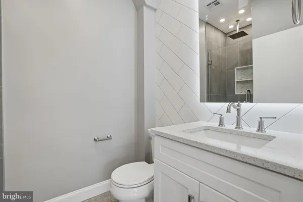 a bathroom with a granite countertop sink a toilet and a mirror
