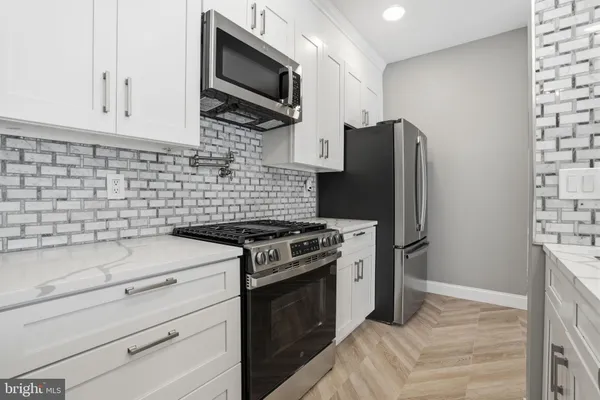 a kitchen with stainless steel appliances white cabinets and a stove top oven