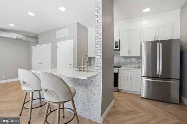 a kitchen with stainless steel appliances granite countertop a refrigerator a sink and white cabinets