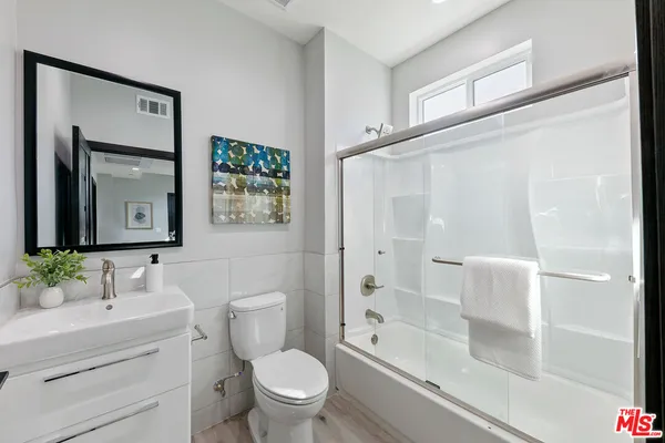 a bathroom with a granite countertop sink a toilet and shower