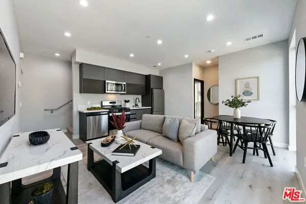 a living room with stainless steel appliances kitchen island a table and a refrigerator