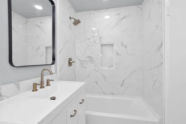 a bathroom with a tub sink and mirror