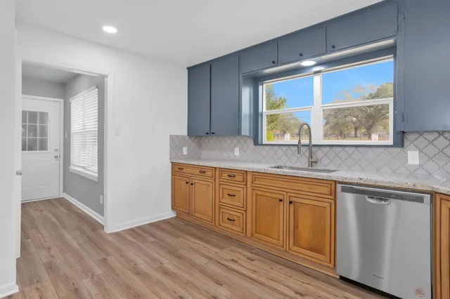 a kitchen with stainless steel appliances granite countertop a sink and cabinets with wooden floor