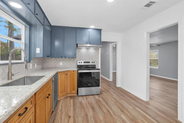 a kitchen with granite countertop a sink stove and refrigerator