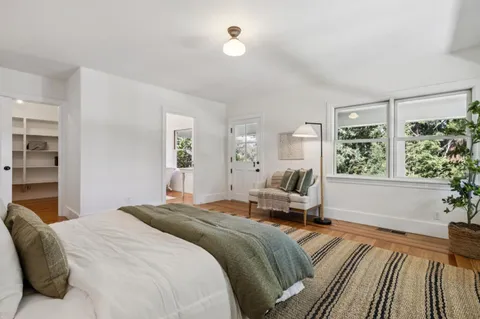 a view of an empty room with wooden floor and fan
