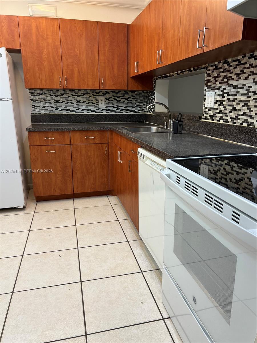 8400 Southwest 133rd Avenue Road, Unit 121 Miami, FL 33183 - Photo 29 of 43 a kitchen with a stove a sink and cabinets