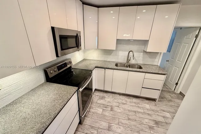 a kitchen with granite countertop stainless steel appliances a refrigerator a stove top oven a sink and cabinets