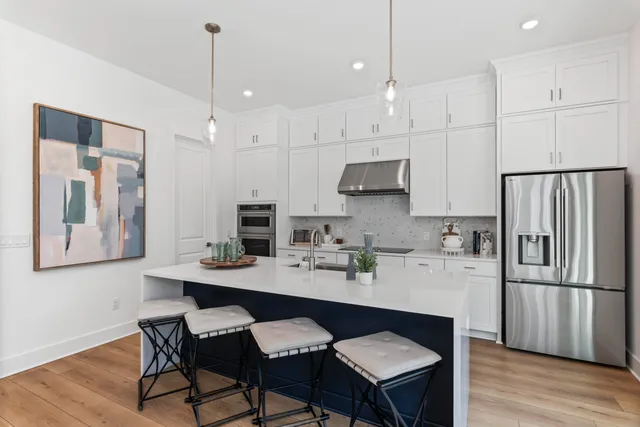 a kitchen with stainless steel appliances granite countertop a sink a stove a refrigerator and island with wooden floor