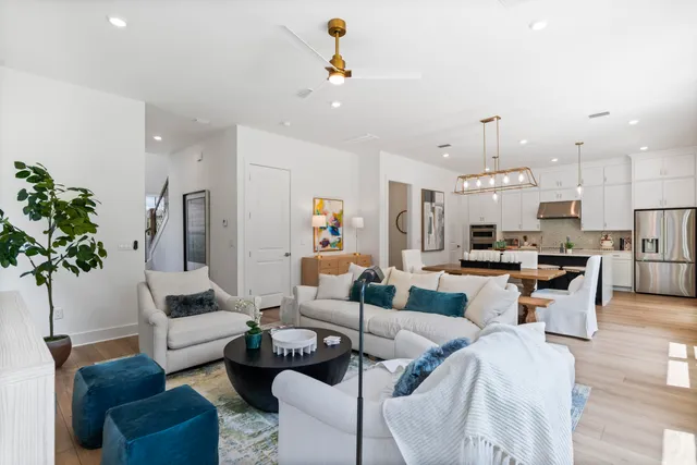a living room with furniture kitchen view and a chandelier