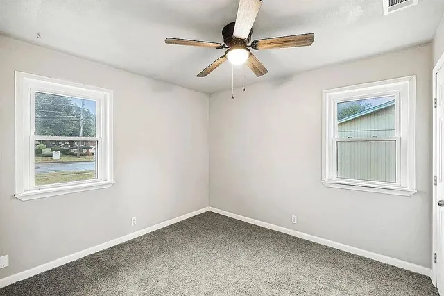 an empty room with a window and a fan