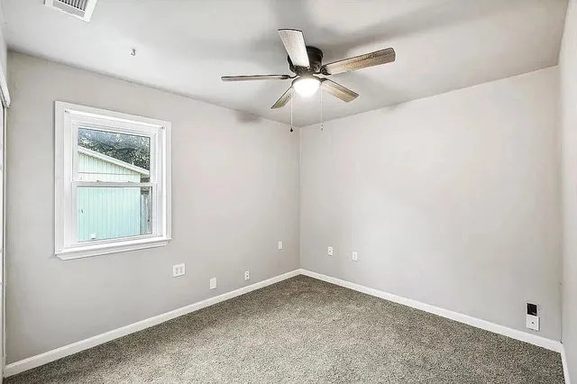 an empty room with a window and a fan