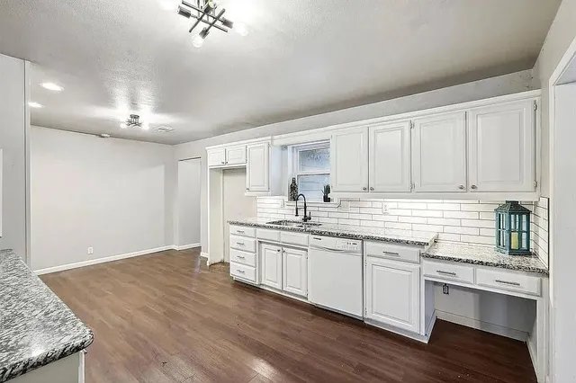 a kitchen with stainless steel appliances granite countertop a sink cabinets and wooden floor