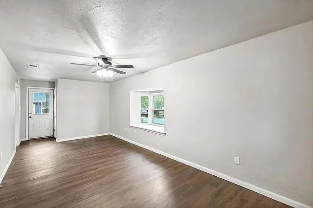 a view of an empty room with wooden floor and a window